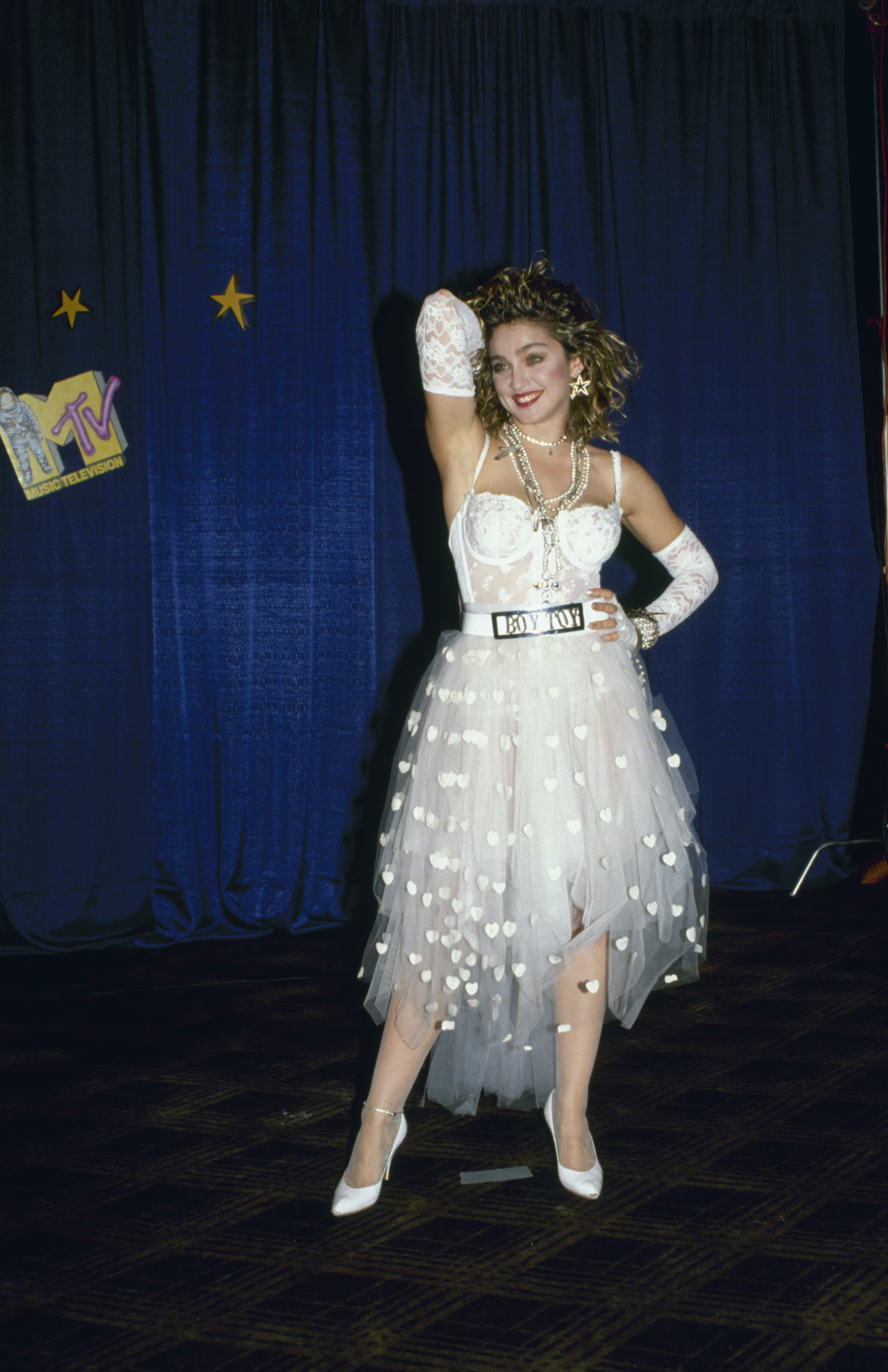 American singer and actress Madonna, dressed in white lace lingerie, pearls, and a 'Boy Toy' belt buckle, stands with one hand on her head and one on her hip at First Annual MTV Video Music Awards, held at Tavern on the Green, New York, New York, September 14, 1984. (Photo by David McGough/DMI/The LIFE Picture Collection via Getty Images)